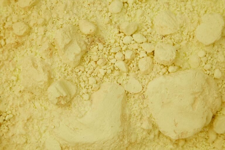 Full frame top view of clean yellow sand with ribbed stones chaotically spread around